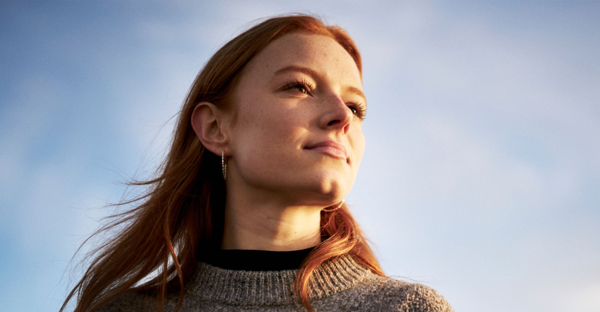 Fotografie von junger Frau, die in den Sonnenuntergang blickt, symbolisierend für die Vision.
